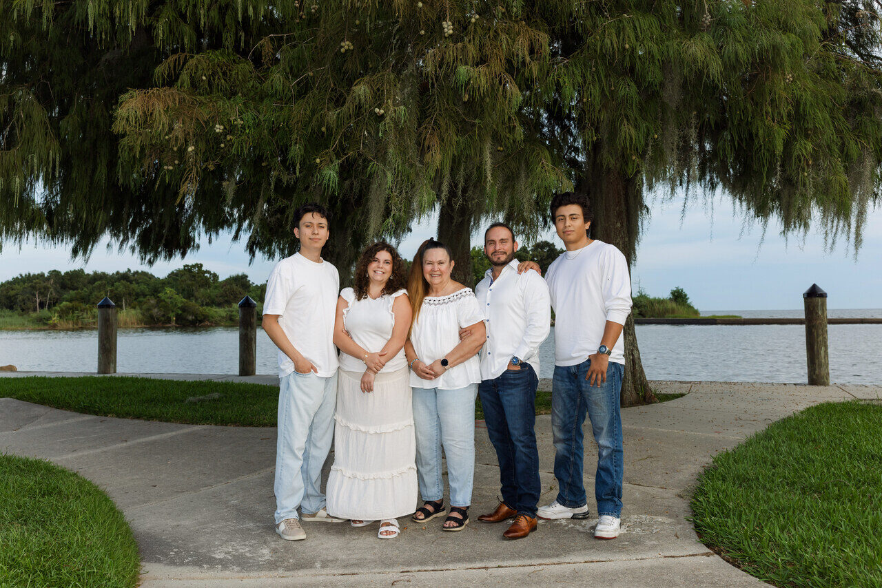 A family of five posing by the lakefront under a live oak