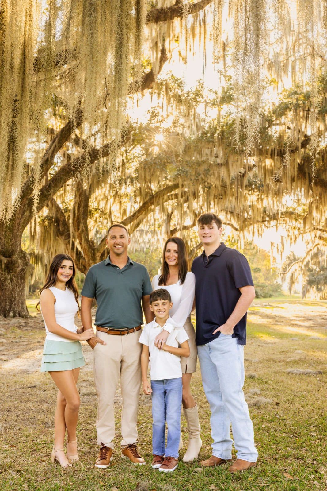 Family of five standing together under a live oak draped in Spanish moss