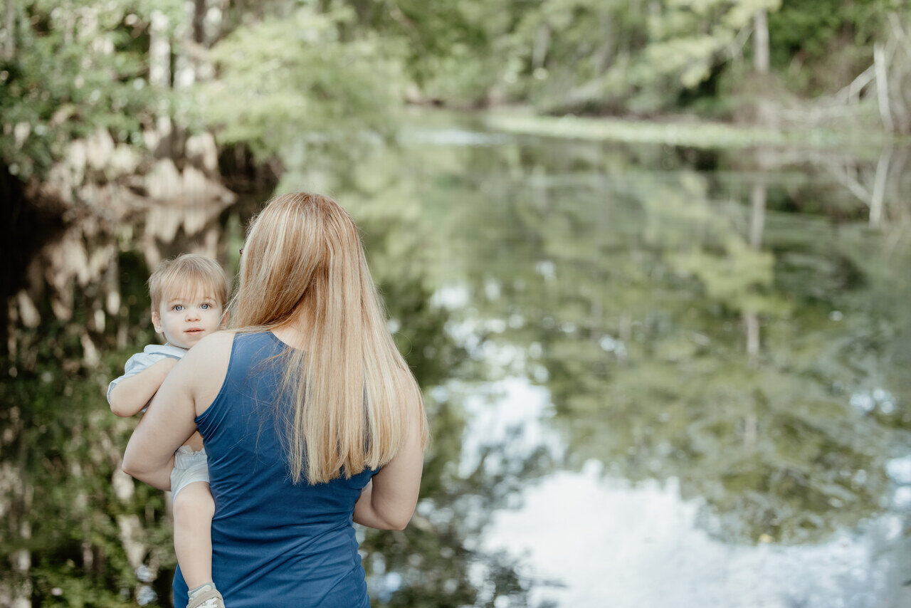 Mother holding her baby beside a quiet bayou