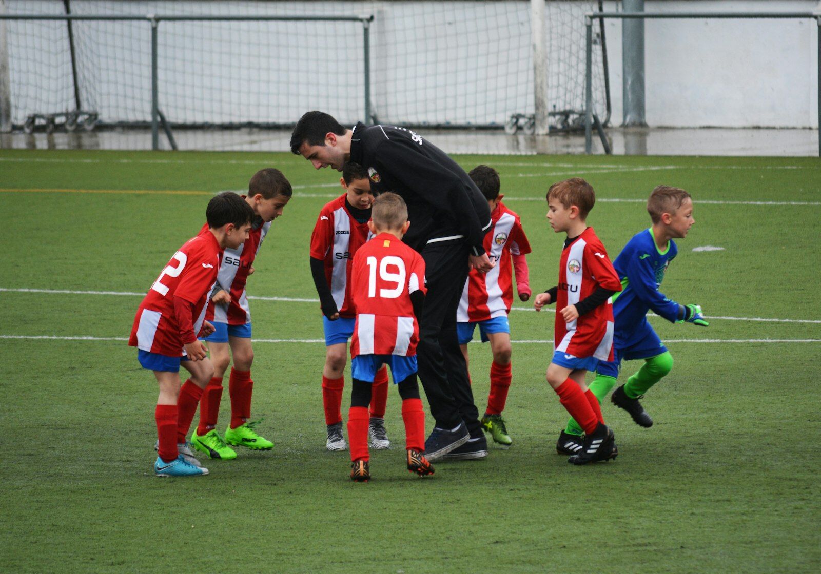 Youth soccer team huddled around their coach on the field